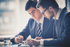 23245353 - image of two young businessmen using touchpad at meeting